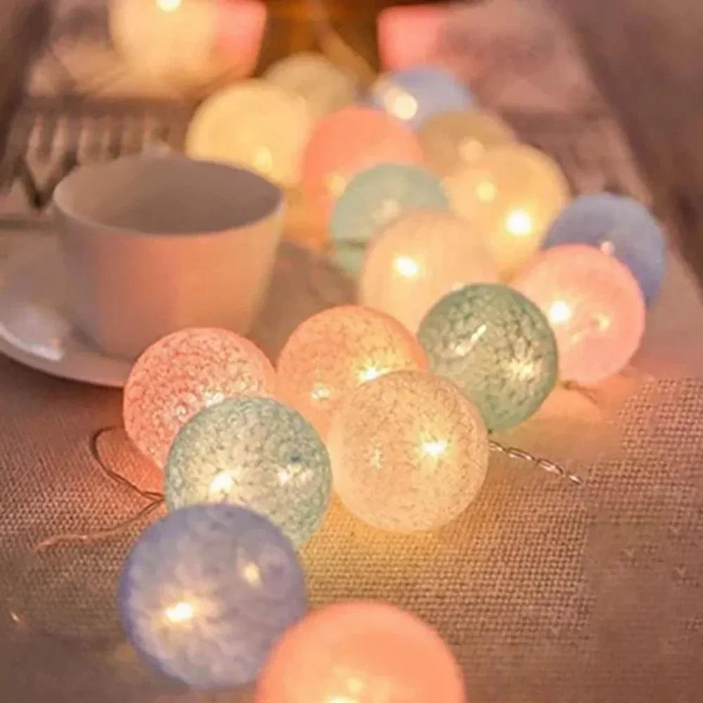 Pastel cotton ball string lights beside a cup
