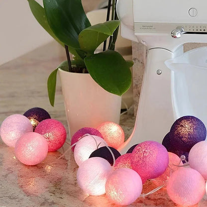 Pink and purple cotton ball garland beside a plant