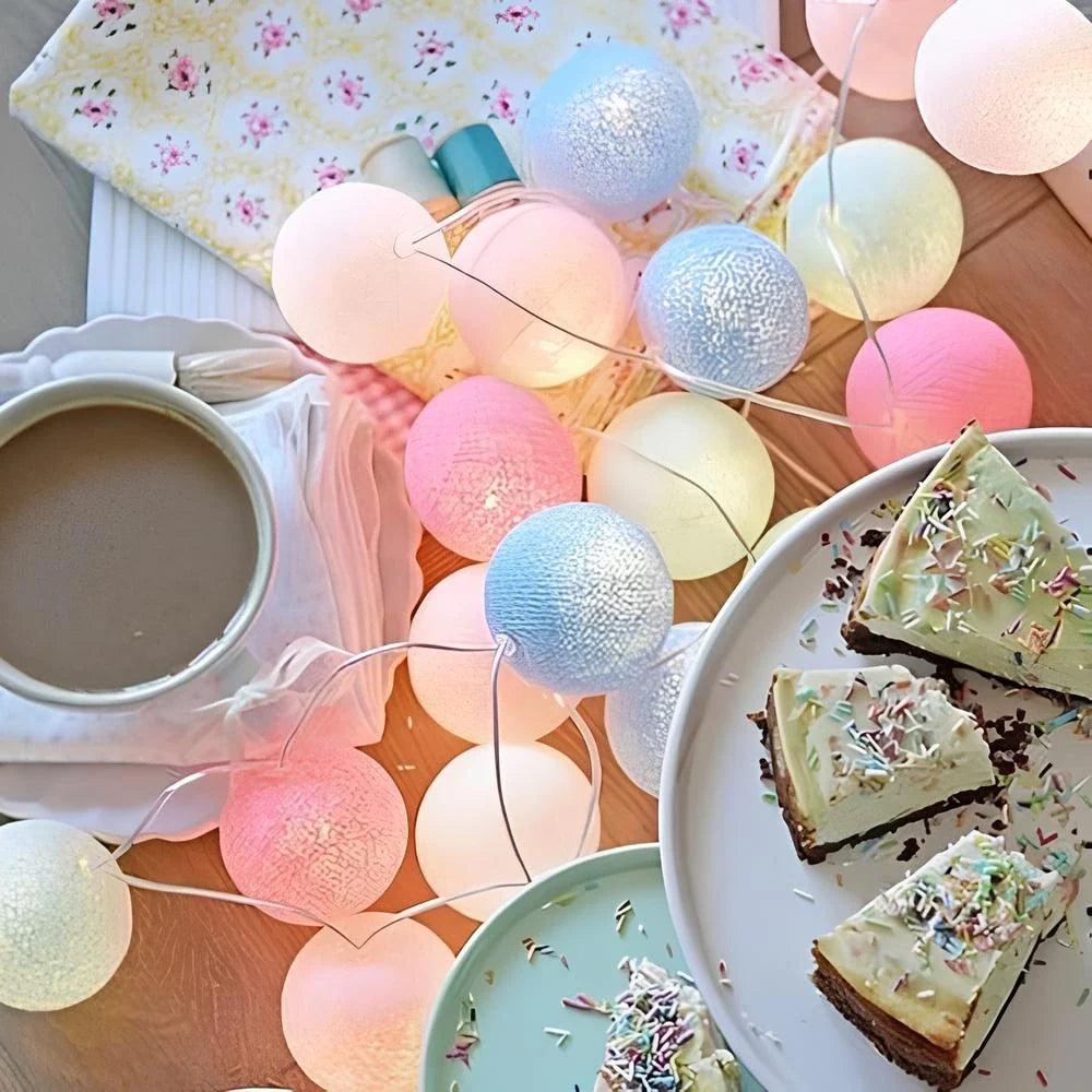 Pastel cotton ball garland arranged around tea and cake