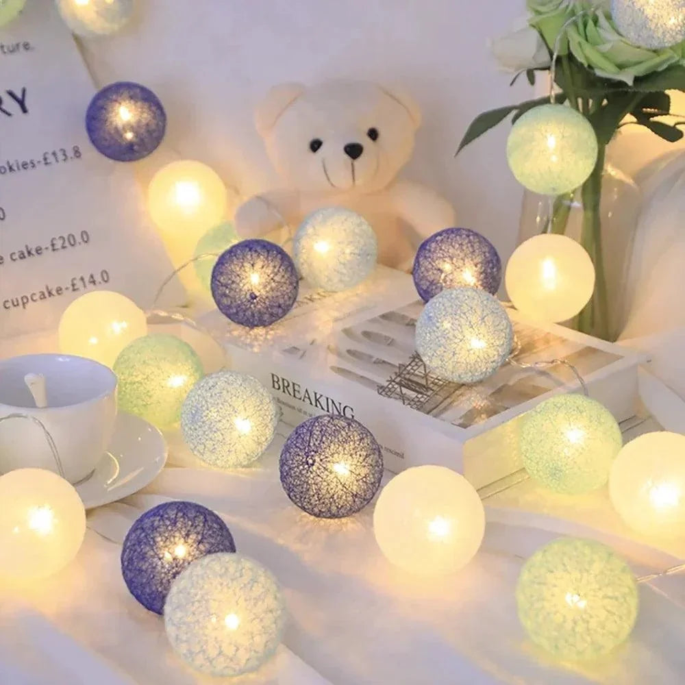 Blue and white cotton ball lights beside a teddy bear