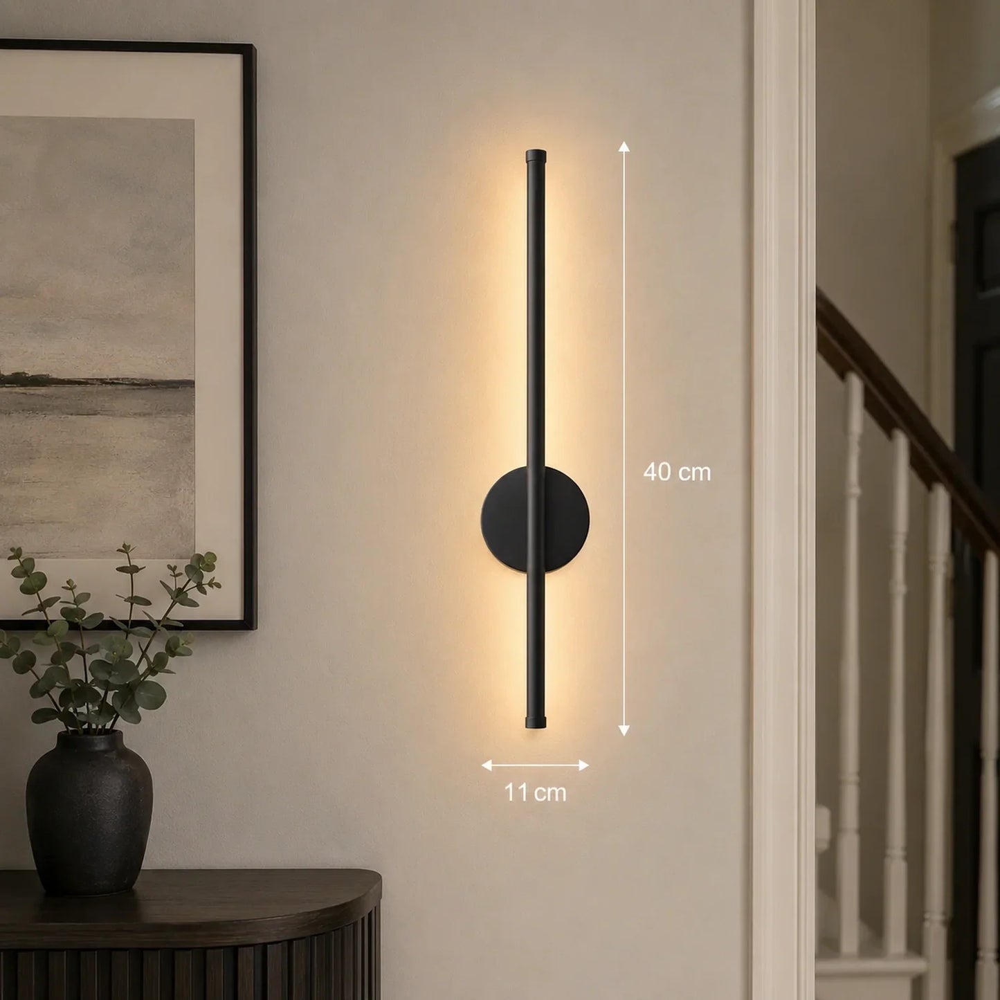 A 40cm black dimmable LED wall light mounted in a hallway, showing dimensions and warm illumination against a neutral wall next to a framed picture.