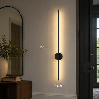 A 100cm tall black linear LED wall light mounted on a neutral interior wall, emitting a warm glow with dimensions indicated for height and width.