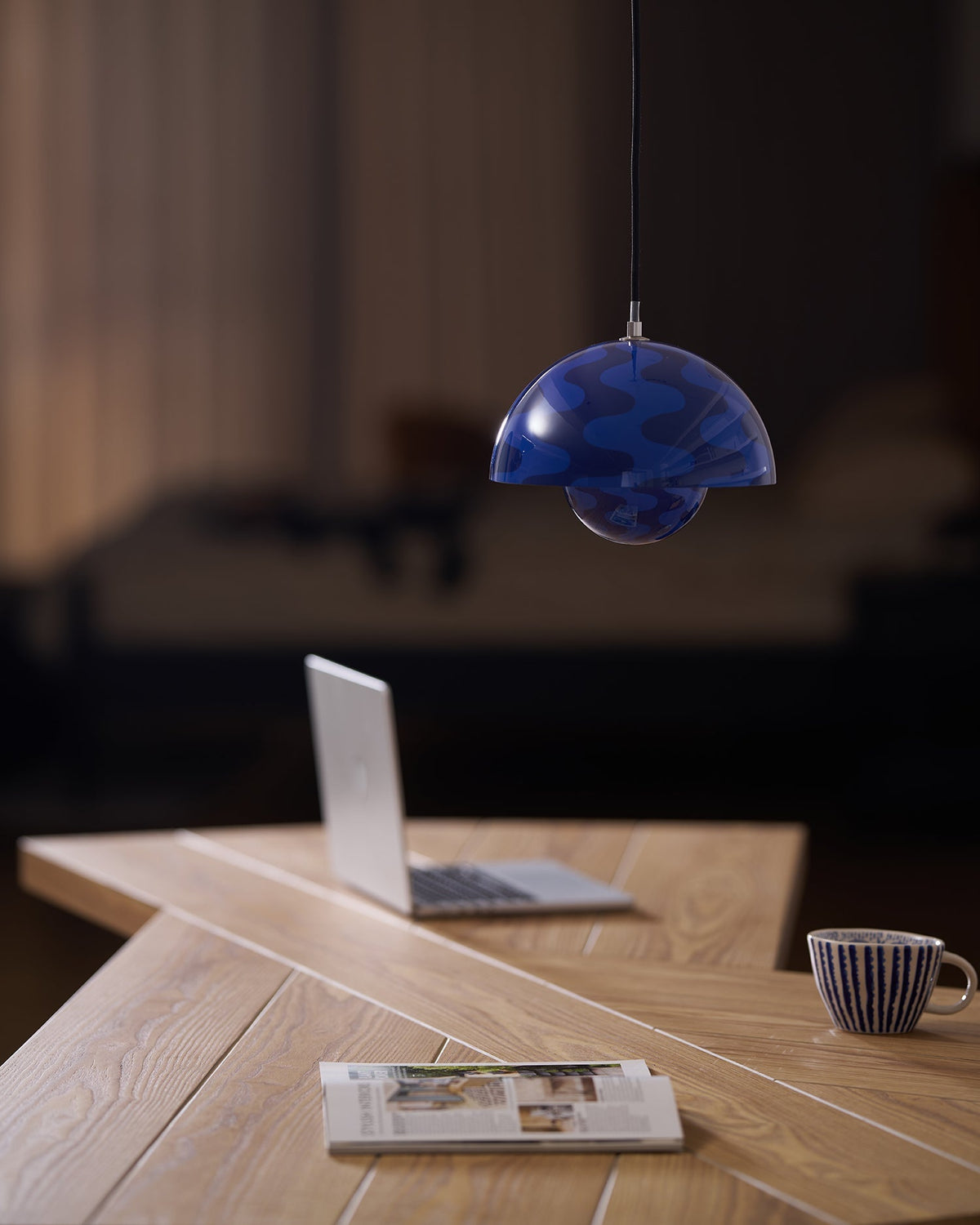 Blue patterned pendant with warm light above a desk