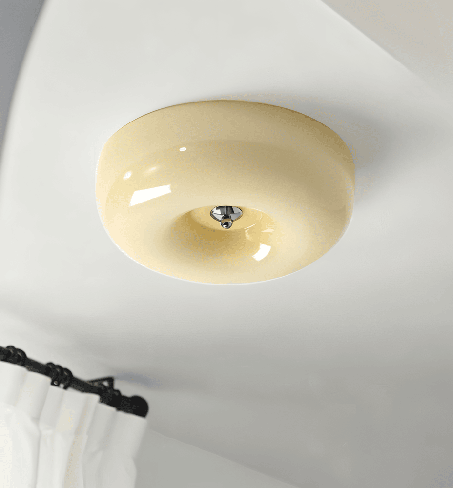 Beige donut glass flush ceiling light mounted above curtains