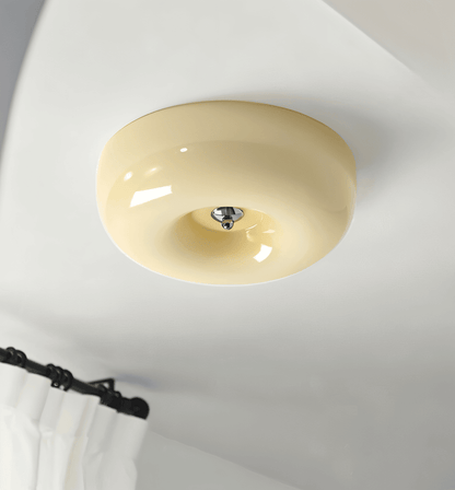 Beige donut glass flush ceiling light mounted above curtains