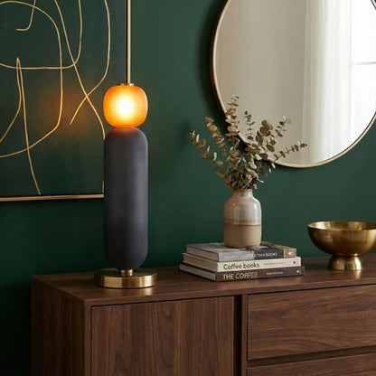 Orange globe and grey body table lamp on a sideboard