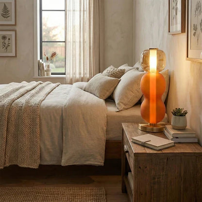 Orange stacked glass lamp beside a bed