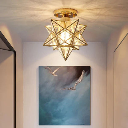 Modern gold and transparent glass five-pointed star flush mount ceiling light casting a warm glow in a hallway above a bird-themed wall art piece.