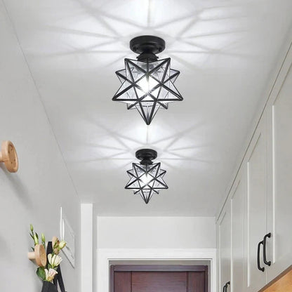 Two modern black and transparent five-pointed star flush mount ceiling lights installed in a bright hallway, casting decorative shadows on the ceiling.