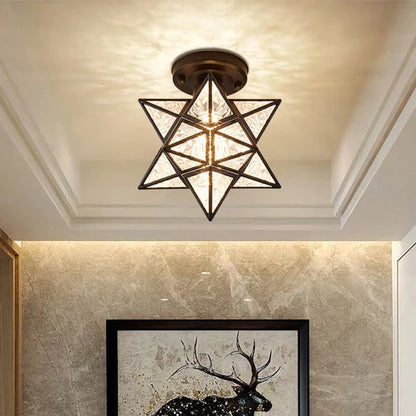 Modern black five-pointed star flush mount ceiling light with textured glass panels emitting a warm glow, installed in a contemporary interior space.