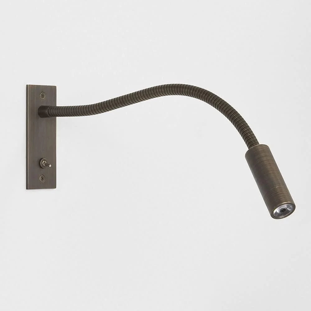 Flexible bronze LED reading wall lamp with a long adjustable neck and a rectangular mounting plate featuring a small toggle switch for bedside use.