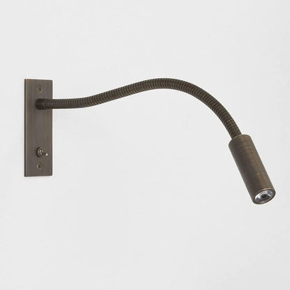 Flexible bronze LED reading wall lamp with a long adjustable neck and a rectangular mounting plate featuring a small toggle switch for bedside use.
