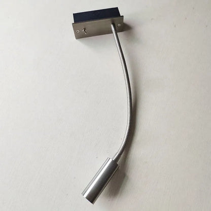 A flexible LED reading wall lamp in a brushed silver finish, featuring a flexible gooseneck arm, a cylindrical light head, and a toggle switch.