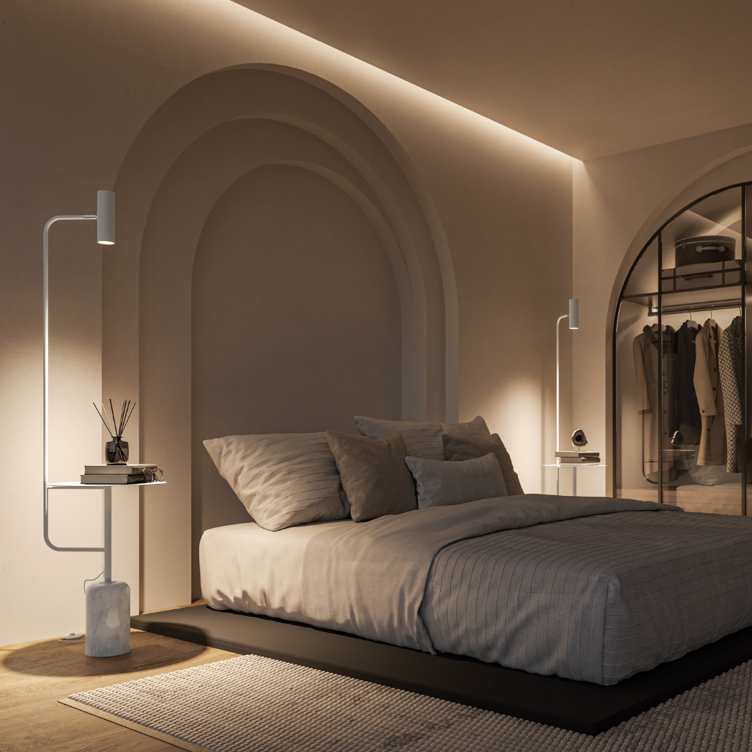 White floor lamp with table beside a bed in low light