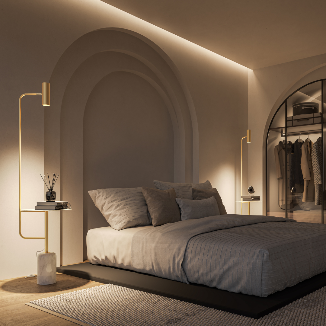 Gold floor lamp with table beside a bed in low light