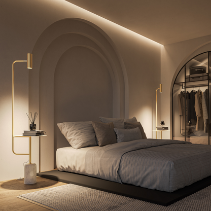 Gold floor lamp with table beside a bed in low light