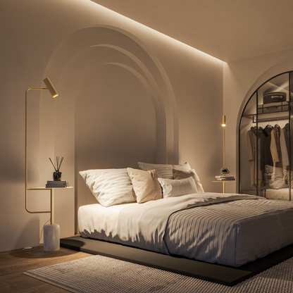 Gold floor lamp with table illuminating a bedside area