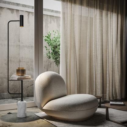 Black reading floor lamp with side table beside an armchair