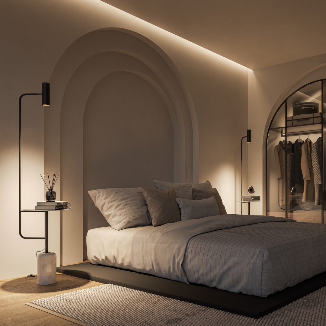 Black floor lamp with table beside a bed in low light