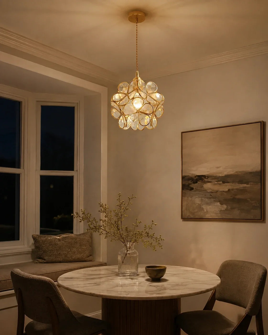 Floral glass petal pendant light with a warm glow, suspended above a marble dining table in a cosy, stylishly decorated room with a window seat.