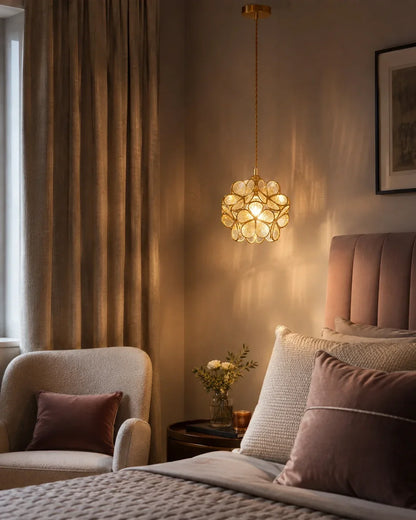 Floral glass petal pendant light with a warm copper finish, casting a soft glow above a cosy bedroom setting with an armchair and bed.