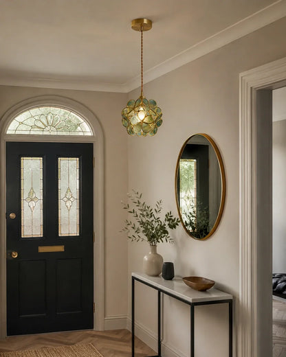 Floral glass petal pendant light with a warm brass finish hanging in a stylish hallway above a console table and oval mirror, creating a cosy glow.