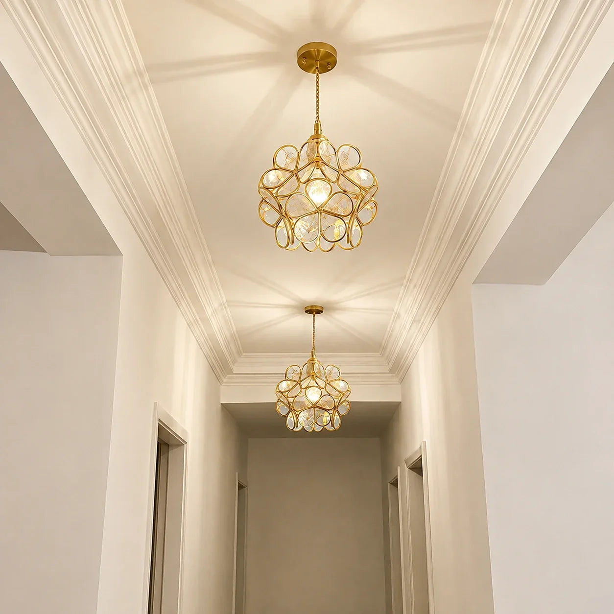 Two decorative floral glass petal pendant lights with metallic frames hanging in a bright, modern hallway with white walls and ceiling moulding.