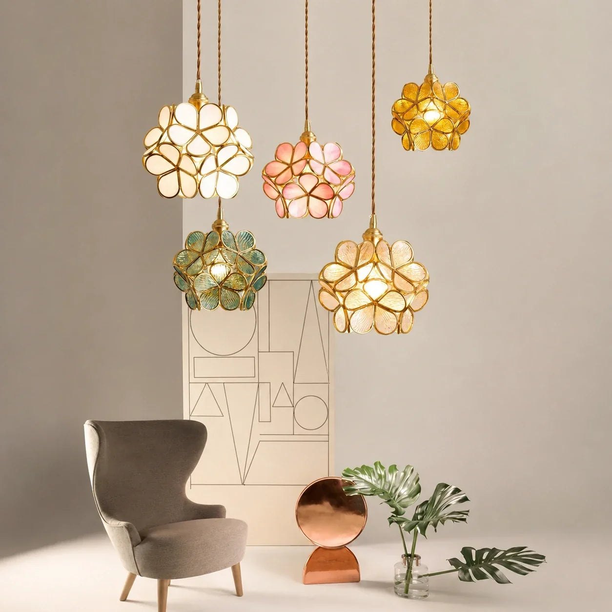 Five multi-coloured floral glass petal pendant lights hanging at varying heights above a grey armchair and copper decorative accents in a modern room.
