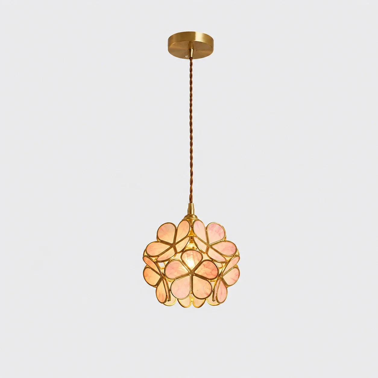Pink floral glass petal pendant light with a metallic finish, featuring a delicate flower-shaped shade suspended by a twisted cable against a plain backgro