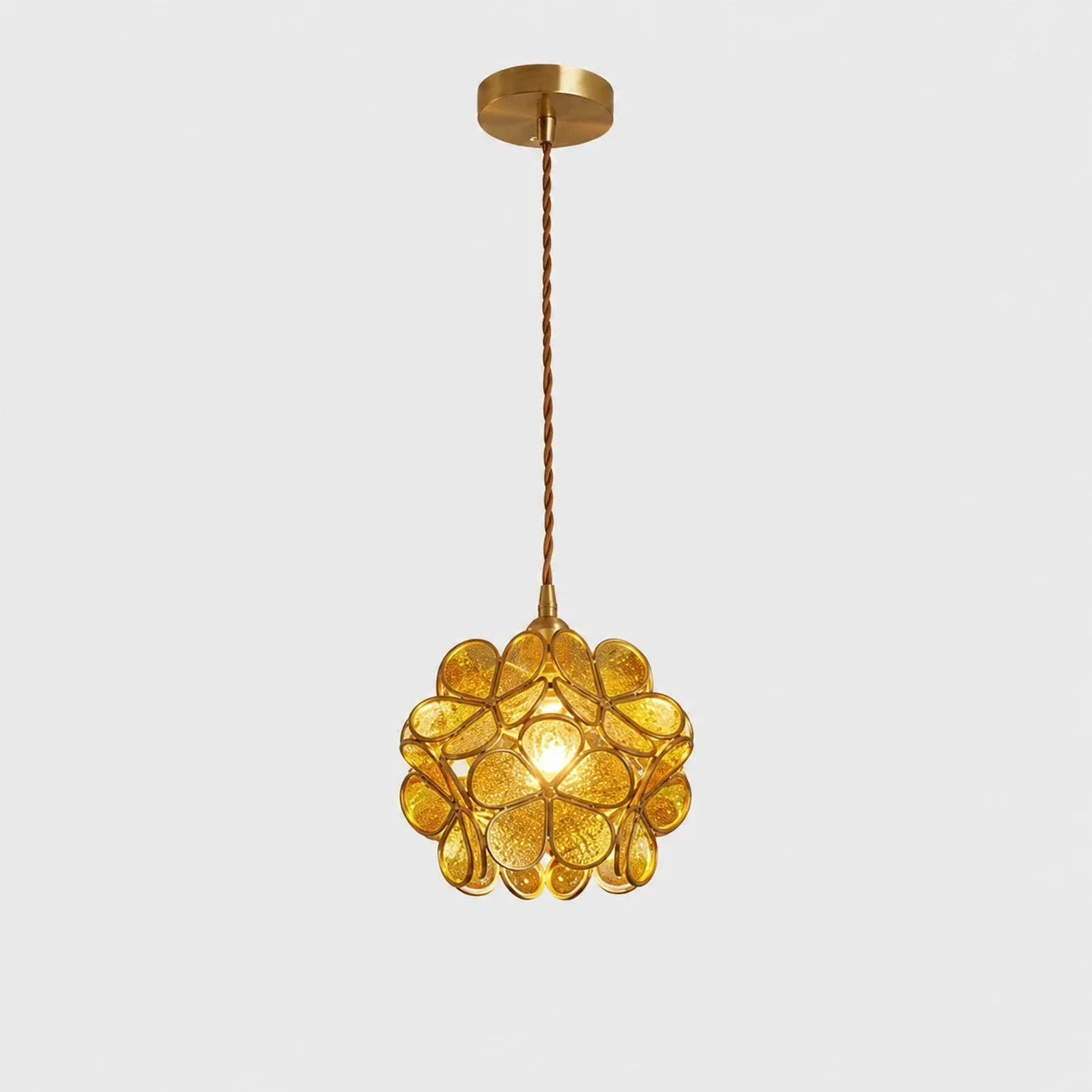 Yellow floral glass petal pendant light with a textured finish, suspended by a twisted cable from a matching metallic ceiling rose on a plain background.