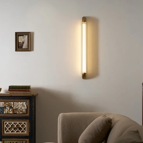 Warm glass tube wall light above an armchair