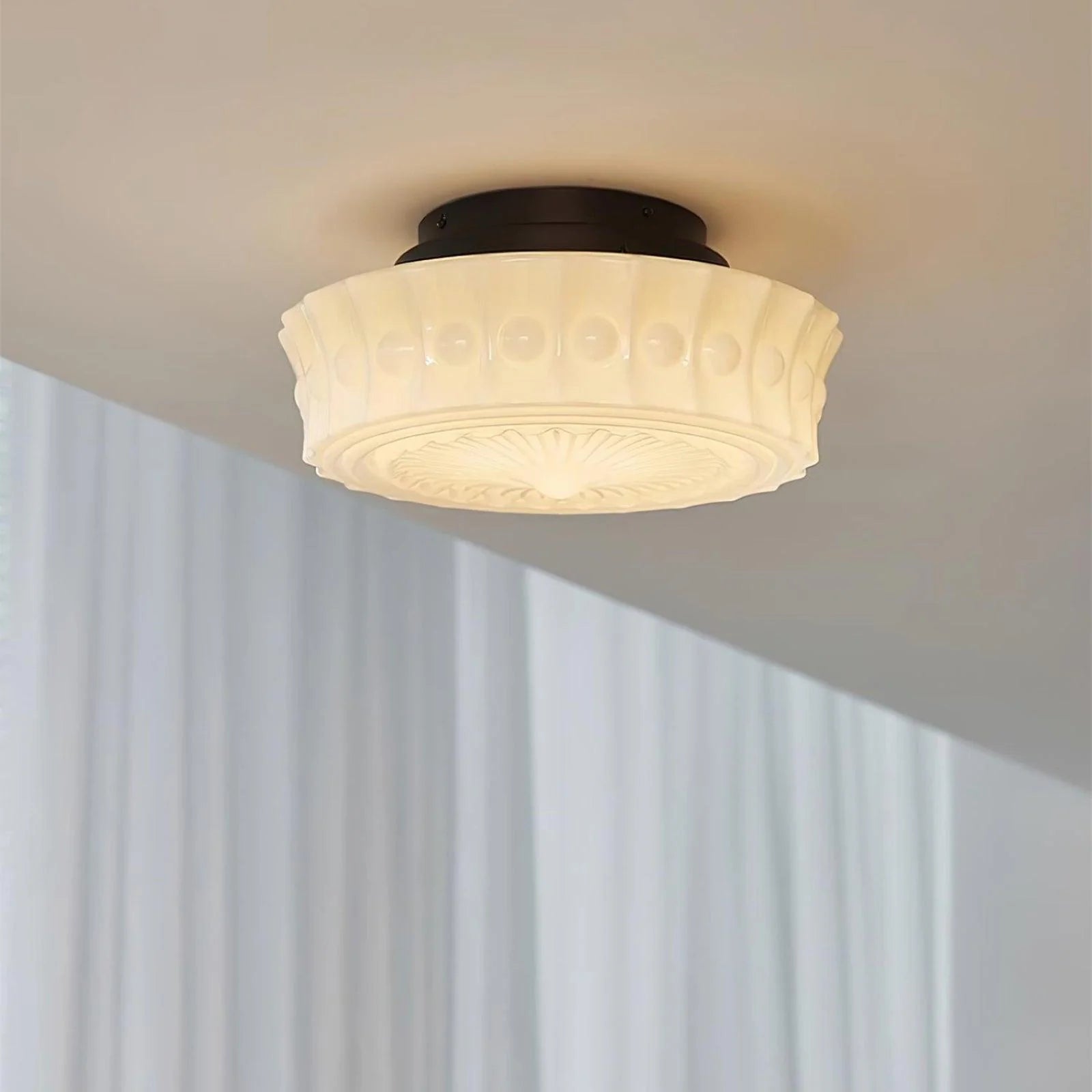 French vintage flushmount ceiling light featuring a decorative cream-coloured glass shade with a textured pattern mounted on a dark circular base.
