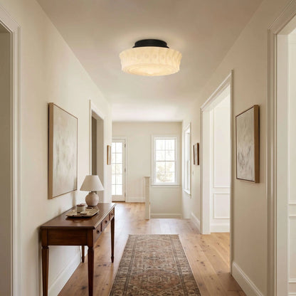 French vintage flushmount ceiling fixture with a textured glass shade installed in a bright, traditional hallway with wooden floors and neutral decor.