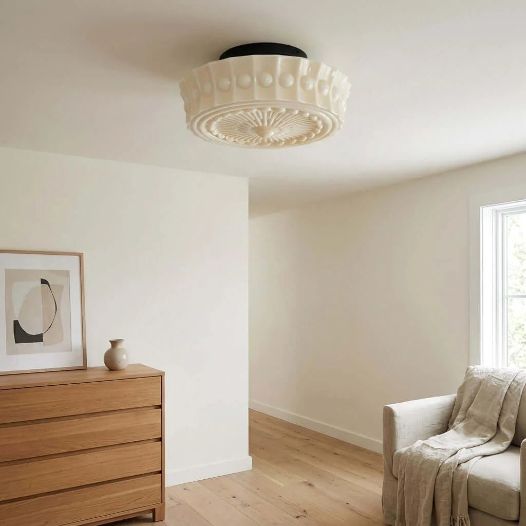 French vintage flushmount ceiling fixture with a decorative cream glass shade installed in a bright, neutral-toned living room with wooden furniture.