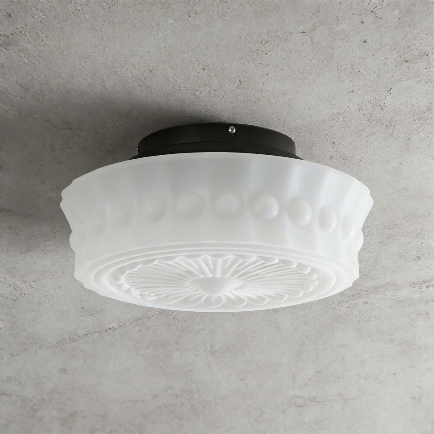 French vintage style flushmount ceiling fixture featuring a white fluted glass shade with a decorative embossed pattern mounted on a dark circular base.