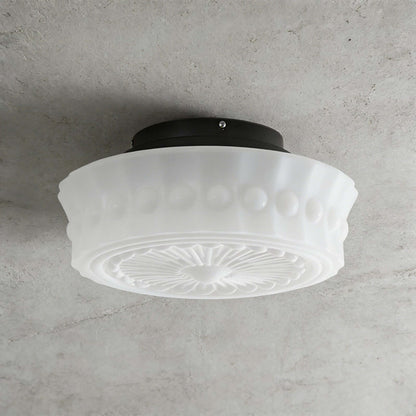 French vintage style flushmount ceiling fixture featuring a white fluted glass shade with a decorative embossed pattern mounted on a dark circular base.