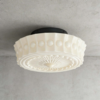French vintage style creamy flushmount ceiling light featuring a decorative fluted glass shade with a central radial pattern mounted on a black base.