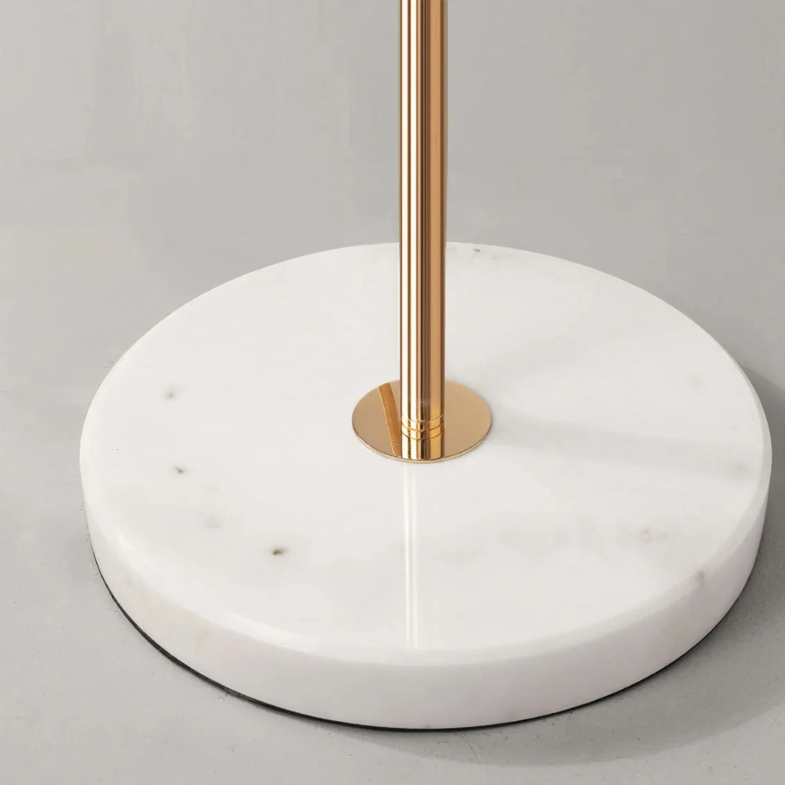 Close-up of the round white marble base and polished gold-coloured metal stem of the Ginkgo Leaf LED floor lamp, showing its sturdy design.