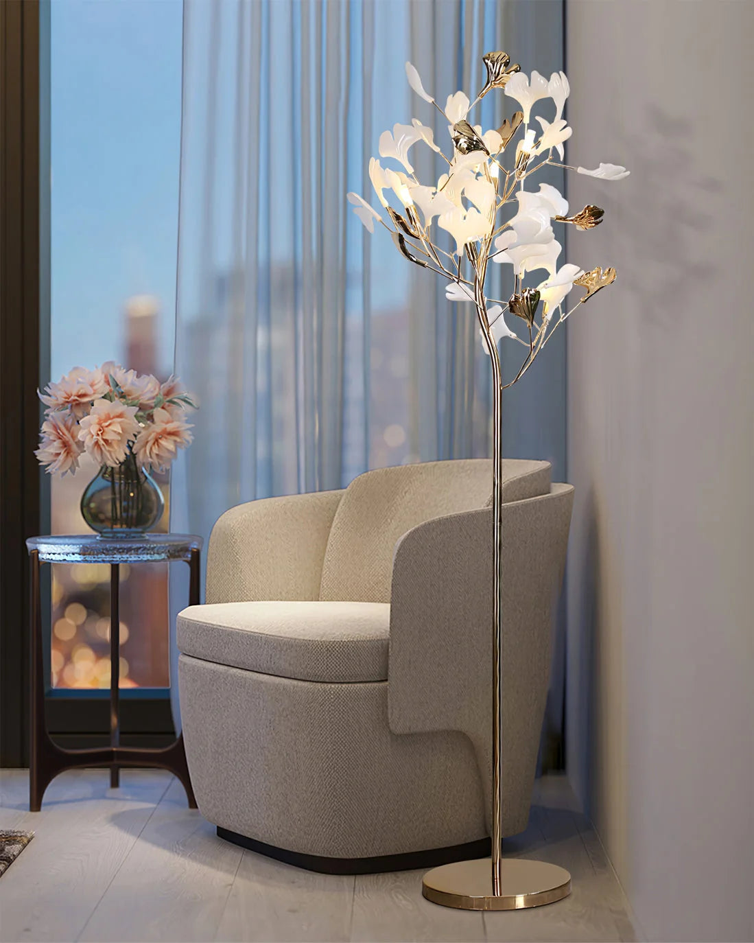 An elegant Ginkgo Leaf LED floor lamp with a gold base and glowing white leaf-shaped lights, positioned next to a modern armchair in a living room.