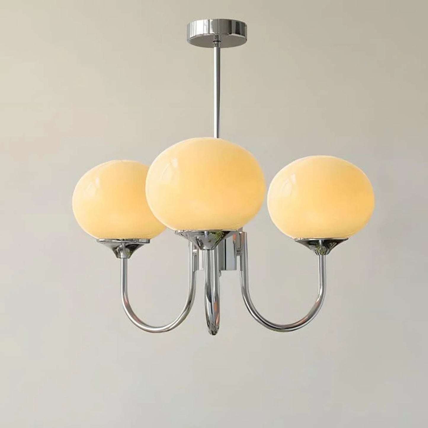 Three-light pendant ceiling light featuring a polished chrome frame and spherical cream glass shades, providing elegant modern interior lighting.