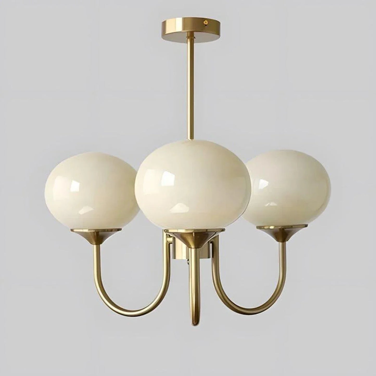 Three-light modern pendant ceiling light featuring smooth cream glass globes suspended from a sleek copper-toned metal frame against a plain background.