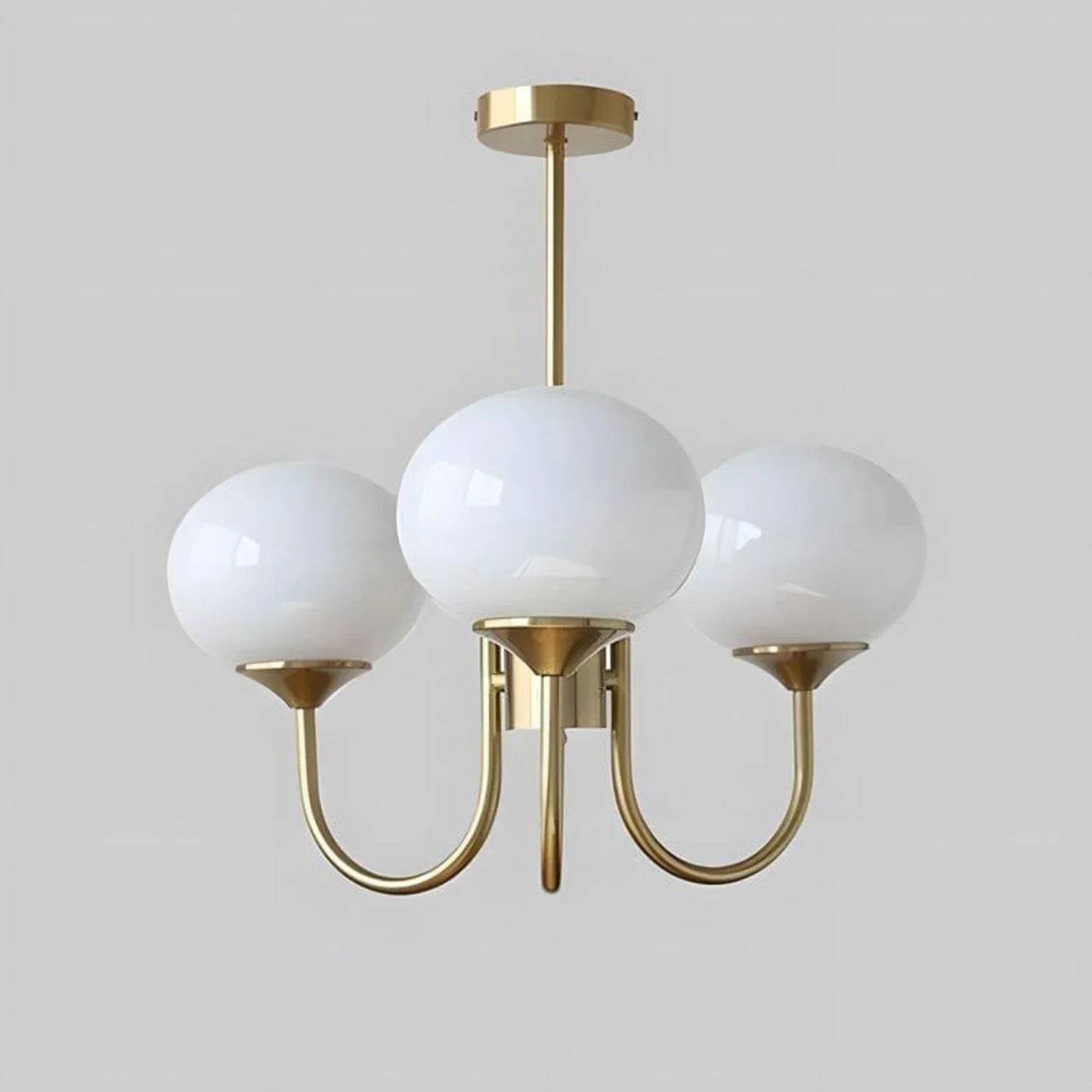 A modern three-light pendant ceiling light featuring three spherical white glass globes supported by a curved, gold-coloured metal frame.