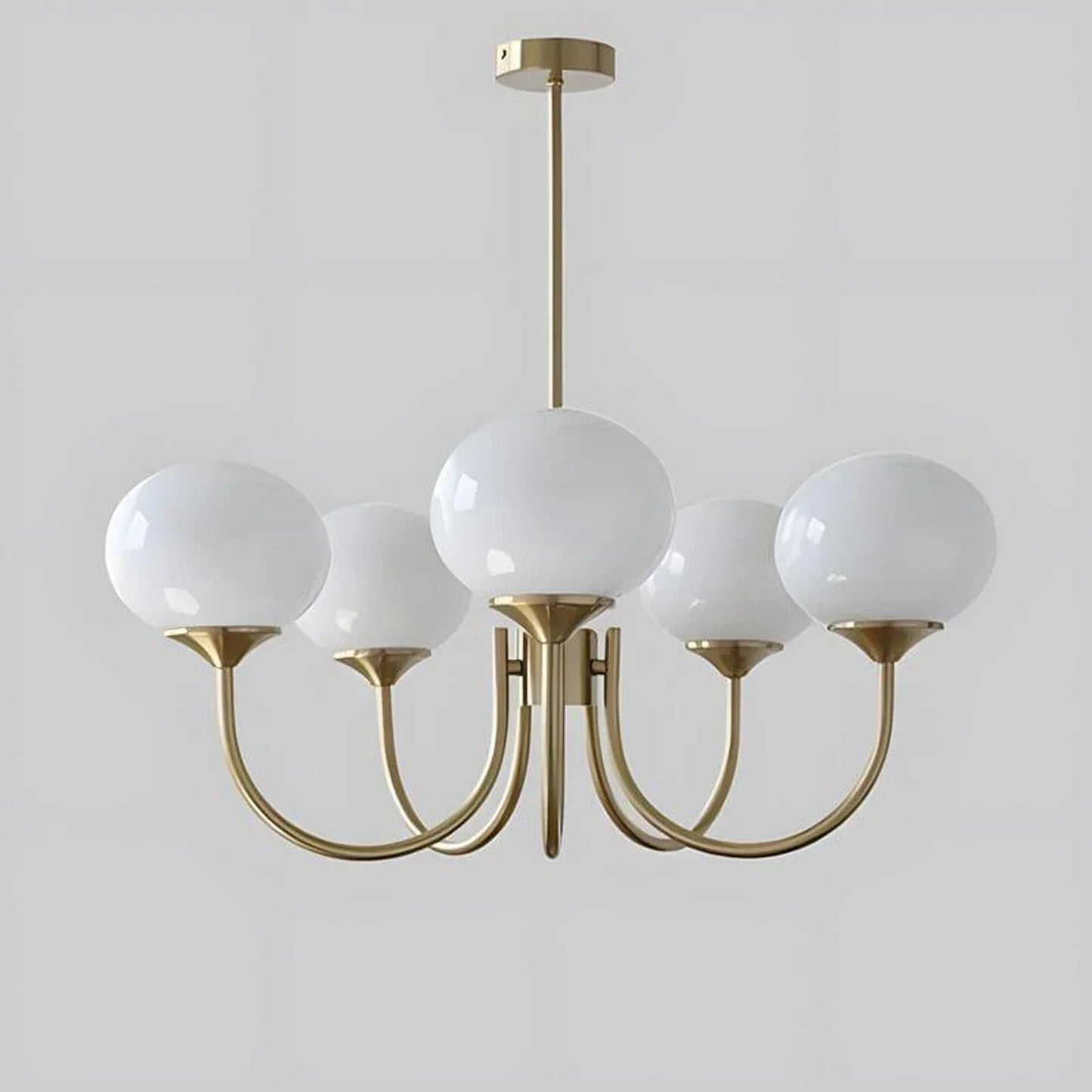 A modern 5-light pendant ceiling fixture featuring five white glass globe shades on curved brass-coloured metal arms against a plain grey background.