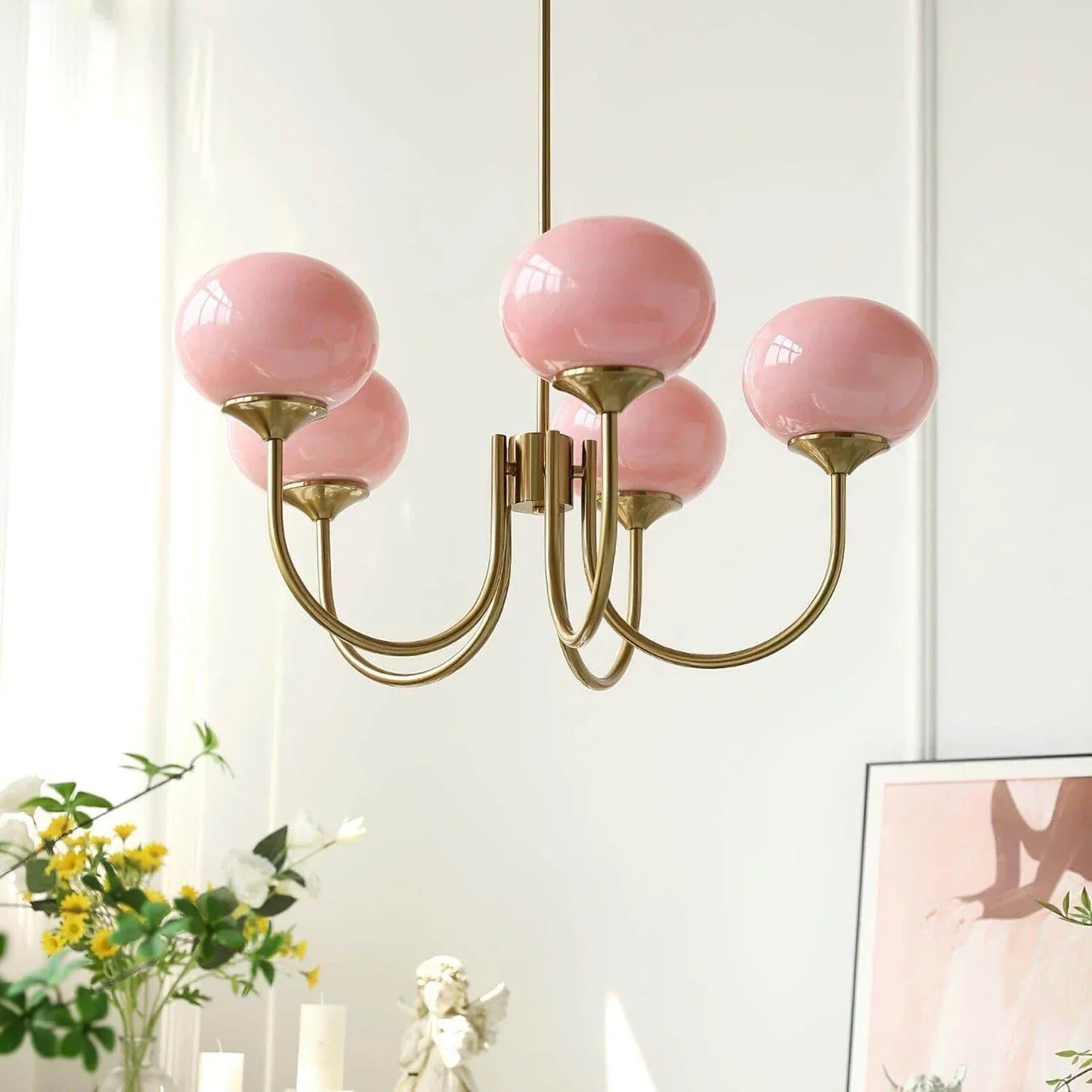Modern ceiling pendant light featuring five glossy pink glass ball shades supported by elegant curved arms with a brushed brass metal finish.