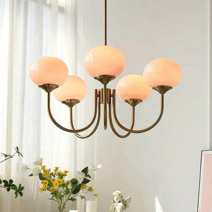 Modern five-arm pendant light featuring glowing spherical glass shades and a polished brass finish, suspended in a bright, contemporary living space.