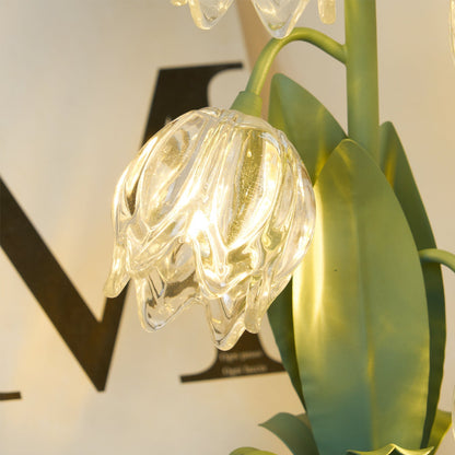 Illuminated glass blossom with green metal leaves