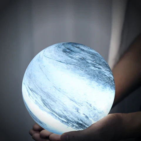 Glass moon lamp held in a hand with cool illumination