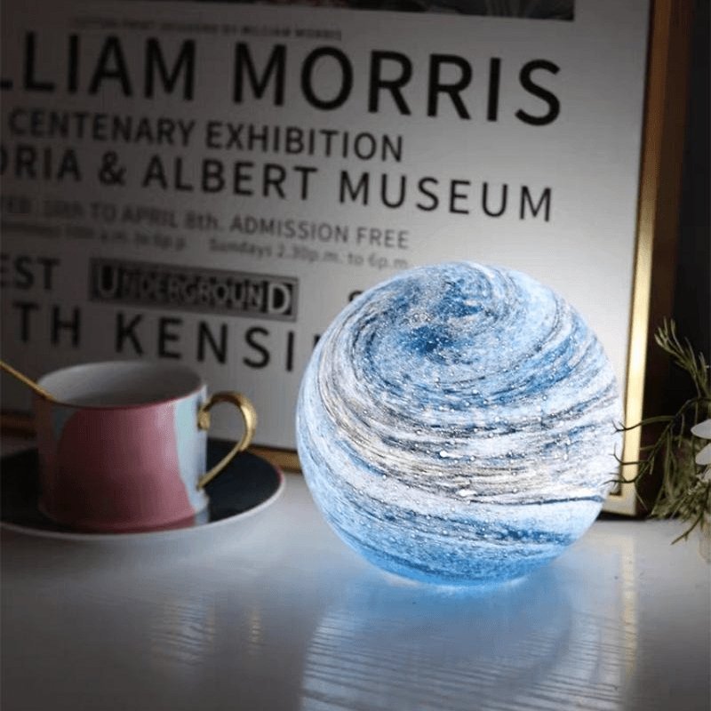 Glass moon table lamp beside books and a mug
