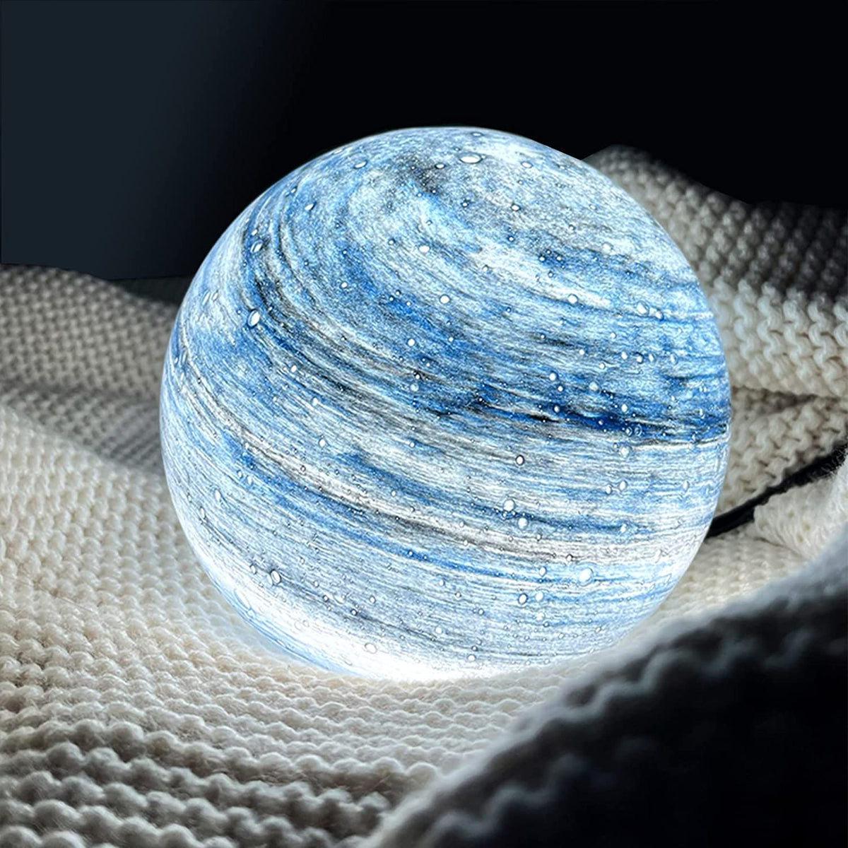 Blue illuminated glass sphere with swirling cosmic detail