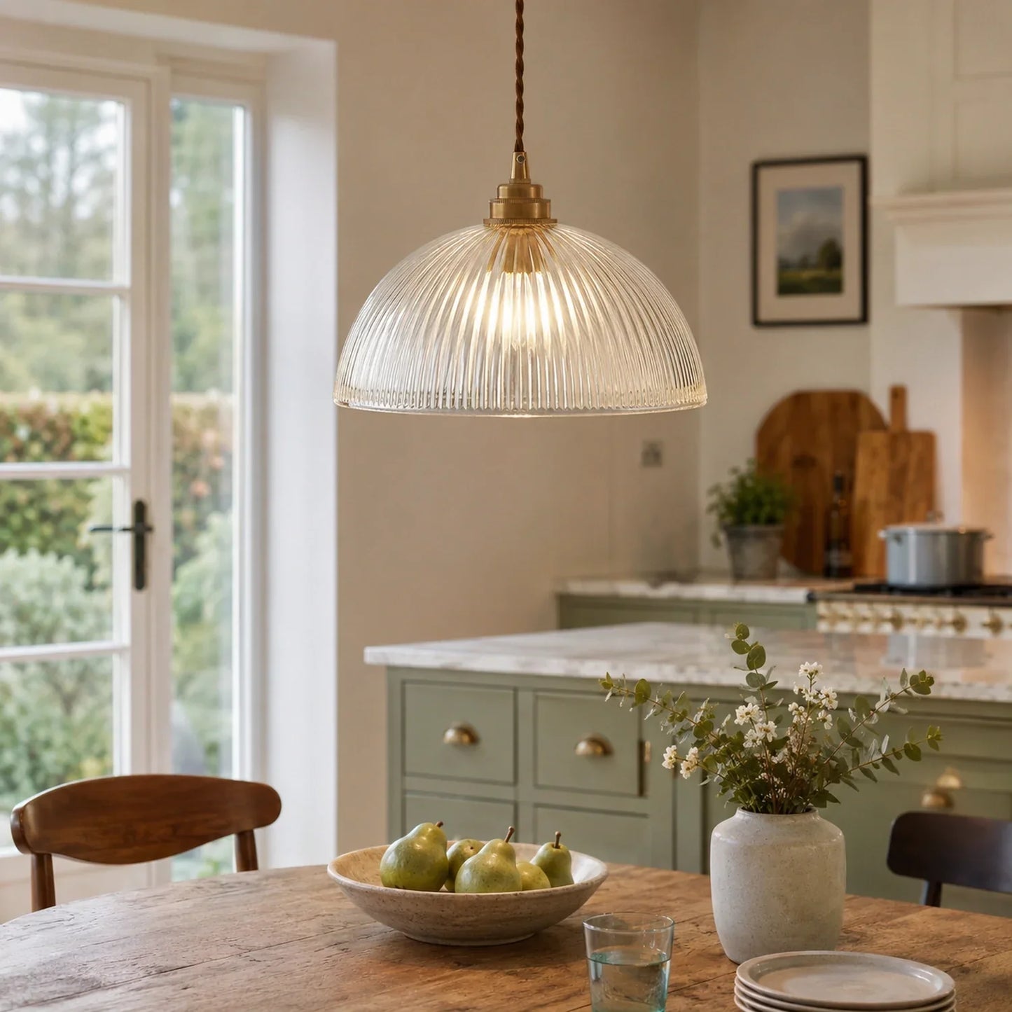 Medium glass pendant light with a ribbed dome shade and brass fitting hanging above a rustic wooden dining table in a modern kitchen setting.